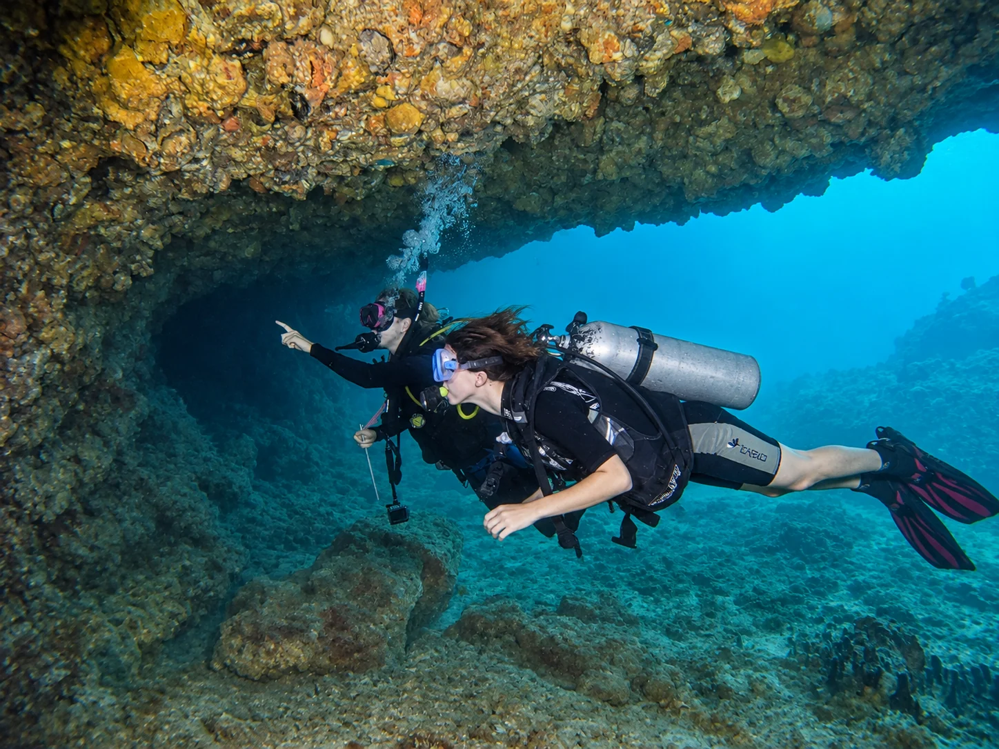A scuba instructor pointing out reef features while guiding a diver